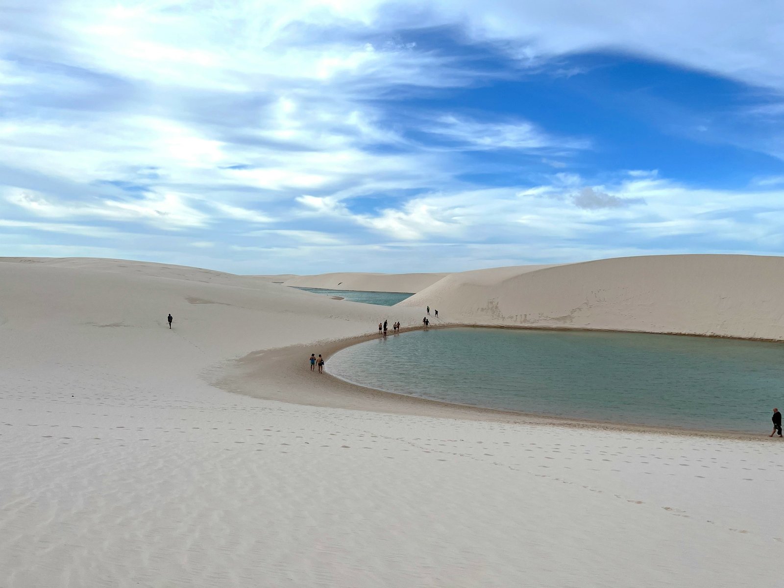 Travelers walking through the dunes and lagoons of Lençóis Maranhenses
