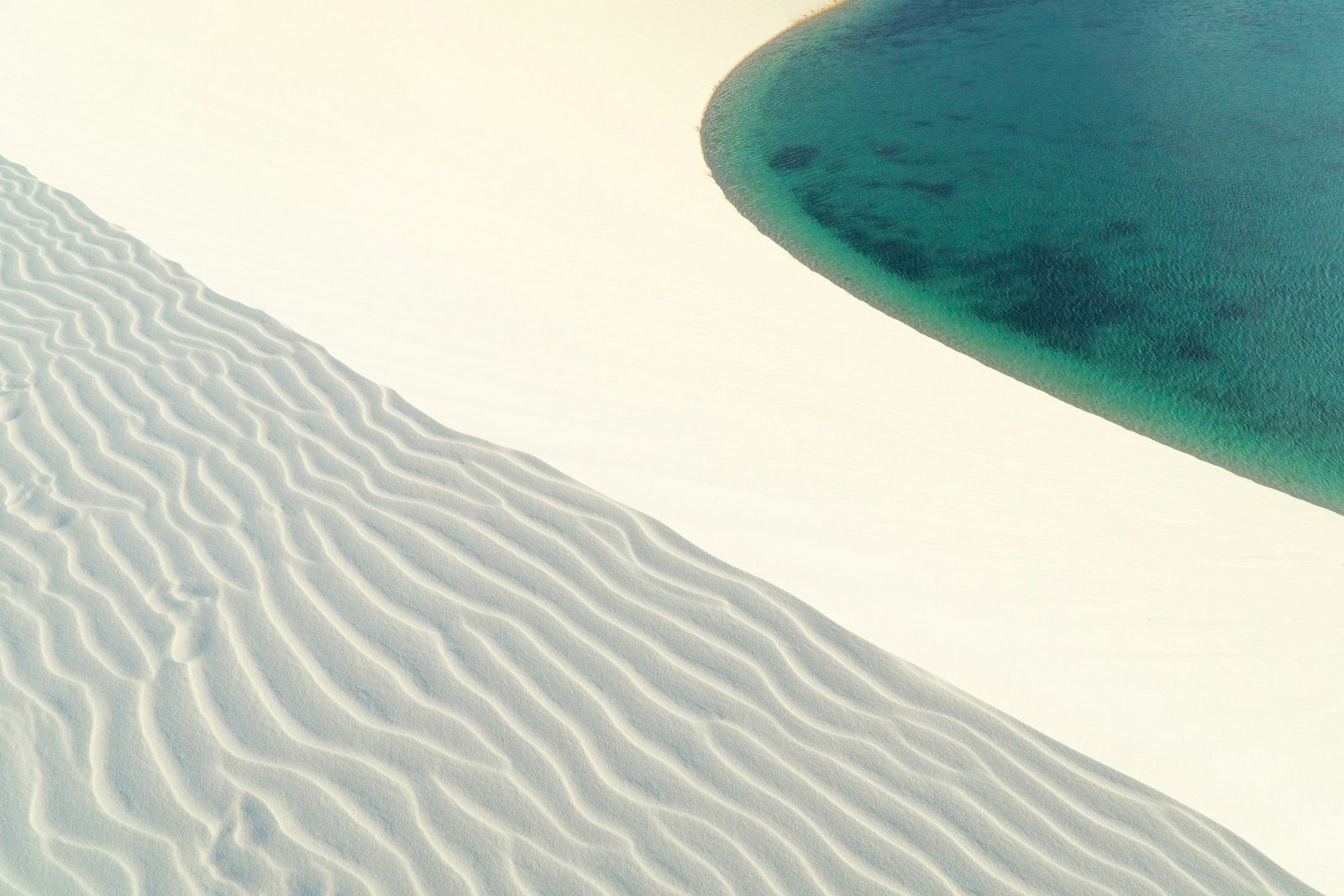 Emerald lagoon curving between white dunes, Lençóis Maranhenses