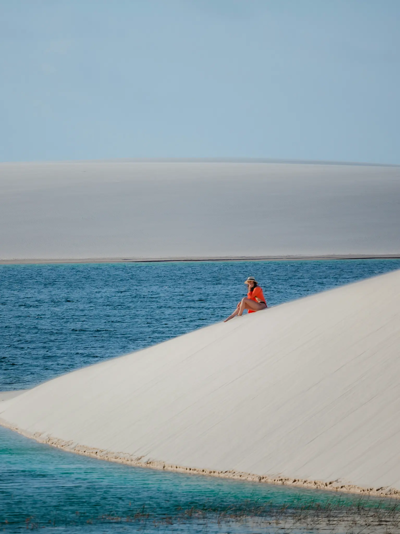 A traveller beside a crystal-clear lagoon in the dunes